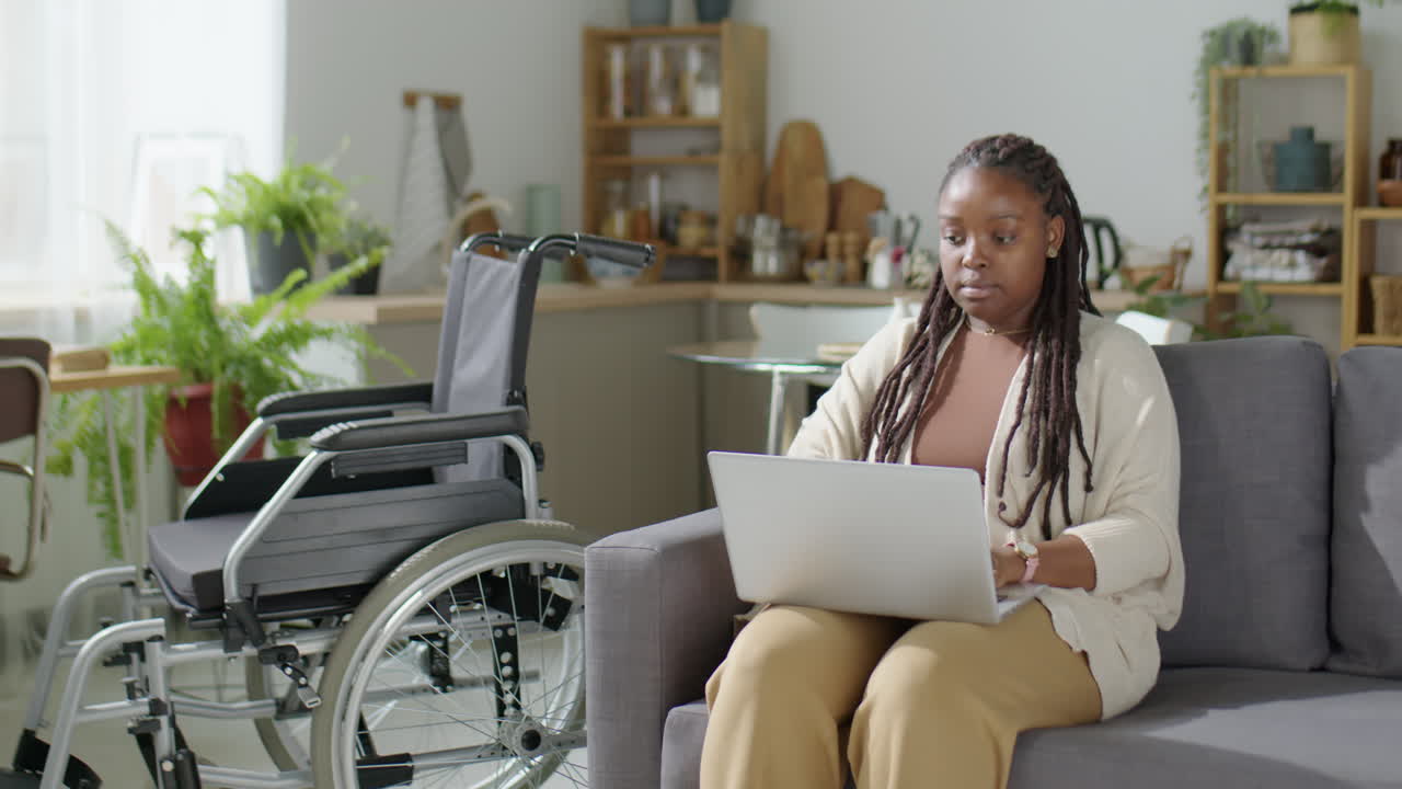 Donna di colore con disabilità che lavora al computer portatile a casa