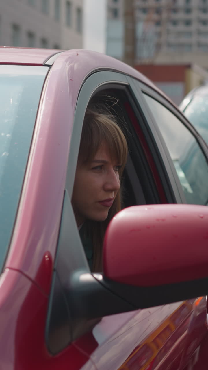 Curious woman looks out of car window to examine road. Driver sits in vehicle getting upset to stuck in created heavy traffic jam in city center slow motion