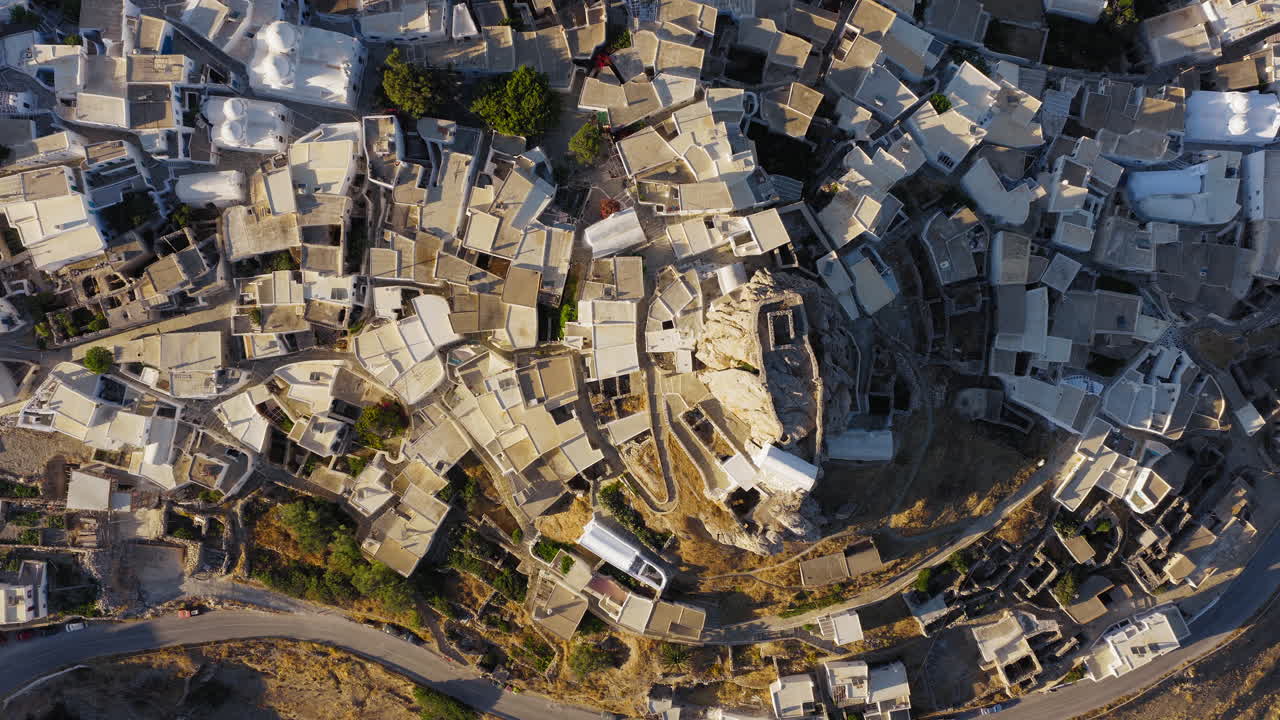 Venetian Castle and Chora village traditional houses flat rooftops at sunrise, Amorgos island, Overhead drone shot