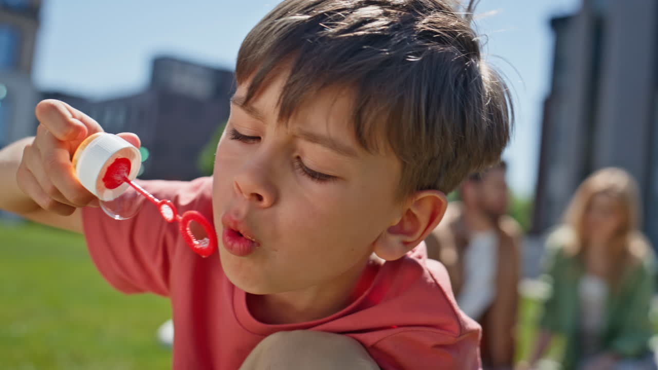 Small boy enjoy blowing soap bubbles outdoor closeup. Carefree child playing