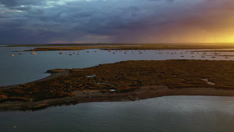 an aerial flight over the salt marshes at west mersea, essex just before a storm with dramatic light over the water