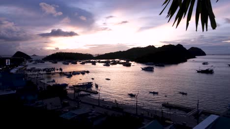 panoramic landscape view of labuan bajo marina, moored boats and tropical islands with twilight dusk sunset on flores island, nusa tenggara region of east indonesia