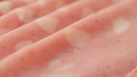 ham italian mordatella, man slices of traditional italian antipasti mortadella sausage on a wooden cutting board, close up macro of chicken or turkey jamon, fat breakfast dish.
