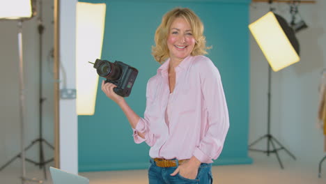 portrait of mature female photographer checking camera before fashion shoot in studio