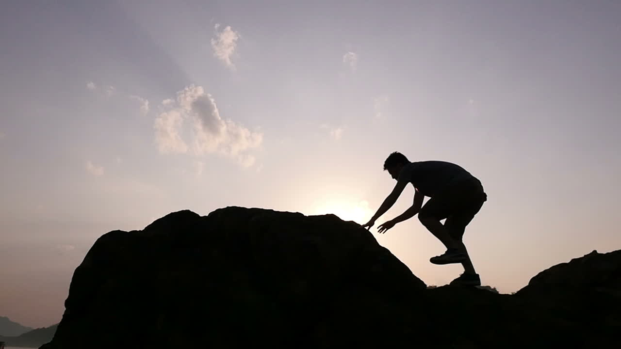Man Climbing and Conquering a Mountain at Sunrise/Sunset