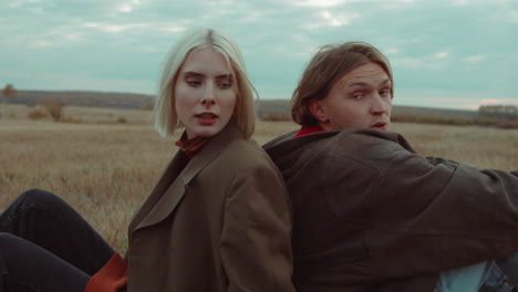 Couple-Sitting-on-Autumn-Field-and-Talking