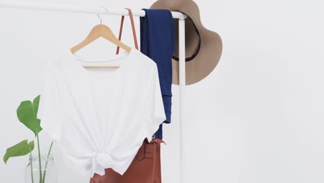 video of white t shirt on hanger with bag, denim trousers and hat and copy space on white background