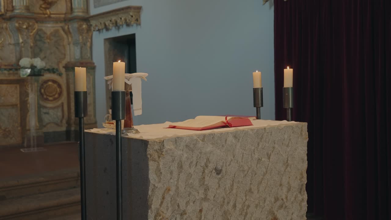 Simple stone altar with burning candles and open bible inside a peaceful historic church