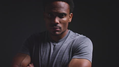 Close-Up-Studio-Portrait-Of-Male-Athlete-Sport-Training-Or-Exercising-In-Gym-Folding-Arms-Against-Black-Background