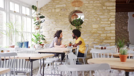 mixed race middle aged couple sitting at table talking in an empty restaurant