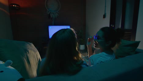 two friends watching tv at home at night