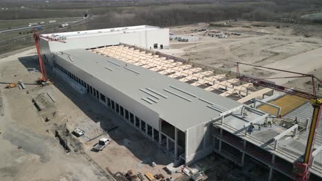 drone shot of a large warehouse being built, showing structural work and surrounding industrial area