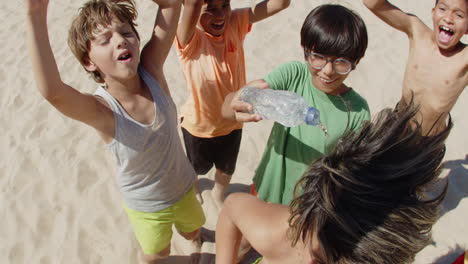 close-up shot of happy boy pouring water on friends head