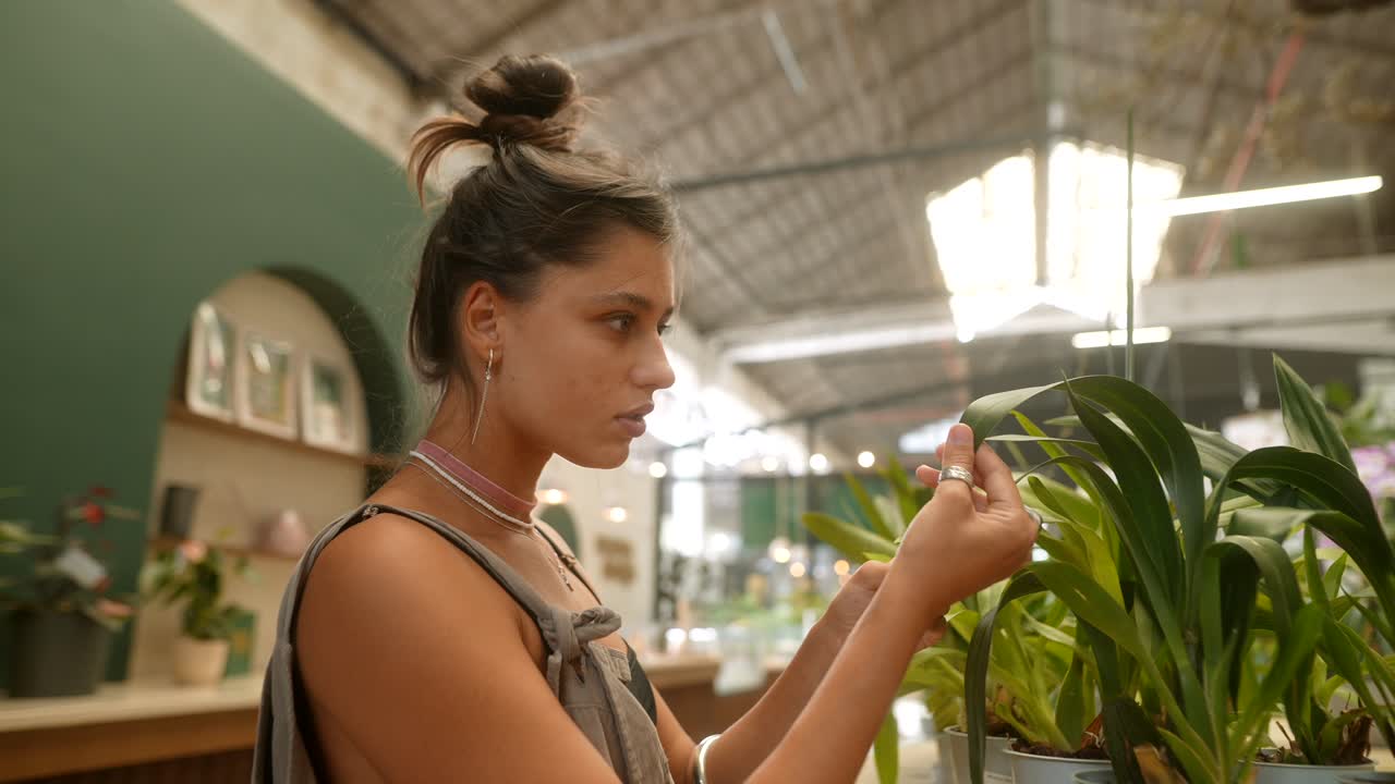 Woman examining orchids and plants in an indoor setting