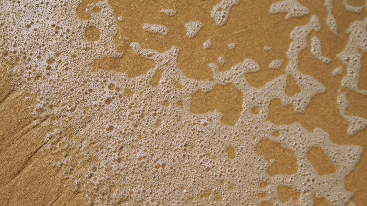 Onde spumeggianti dell'oceano che si infrangono su una spiaggia sabbiosa bagnata