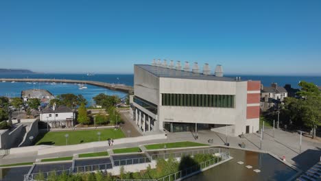 lexicon, dún laoghaire, county dublin, ireland, september 2024. drone descends in a gentle clockwise orbit around the sleek modern building facing dublin bay on beautiful day under a clear blue sky.