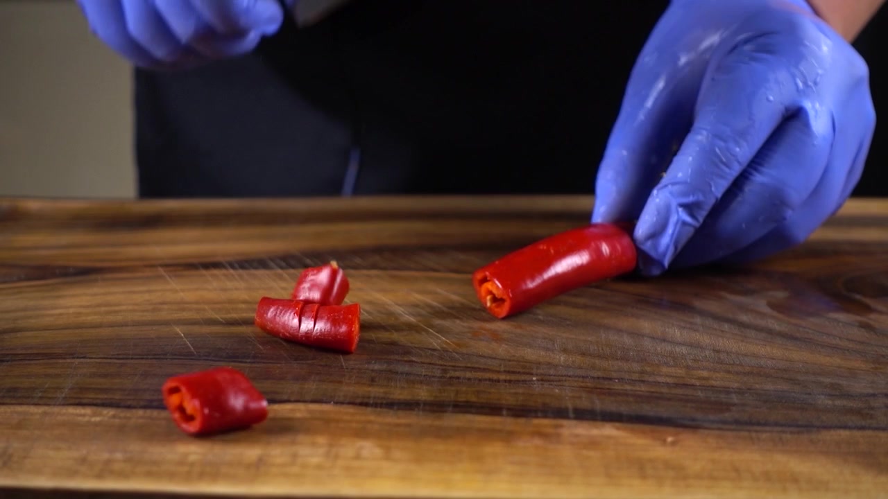 O cozinheiro corta pimenta numa tábua de corte.