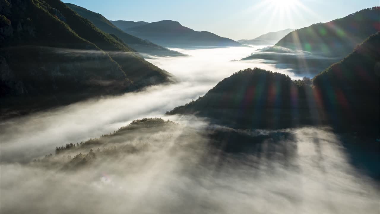 Timelapse of fog in the valley acting like waves in the ocean with the sun beaming through in the background. Durmitor national park in Montenegro