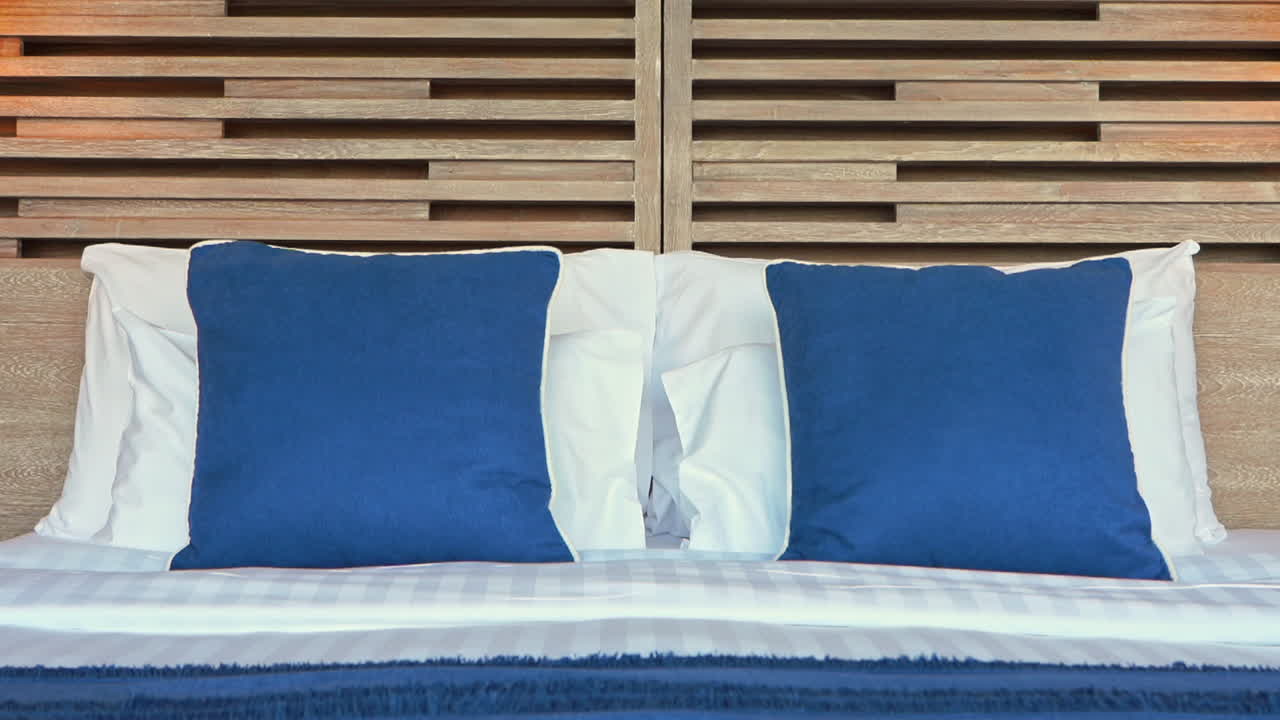 cama de lujo en el dormitorio de un exótico complejo tropical con almohadas azules y blancas, de cerca