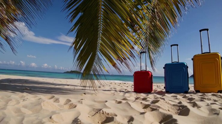 Valigie colorate su una spiaggia tropicale di sabbia bianca sotto le palme