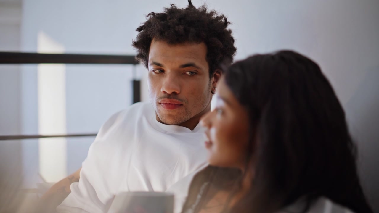 Adolescenti a letto sorseggiano espresso al mattino, primo piano. Coppia innamorata si rilassa