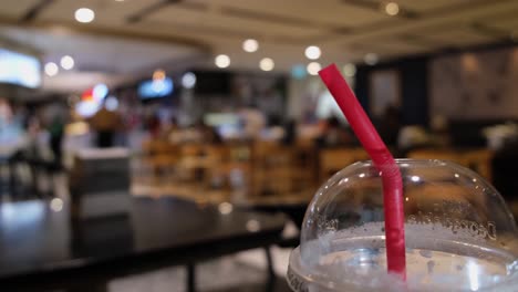 closer capture of the red straw in a plastic disposable cup in a restaurant in bangkok, thailand