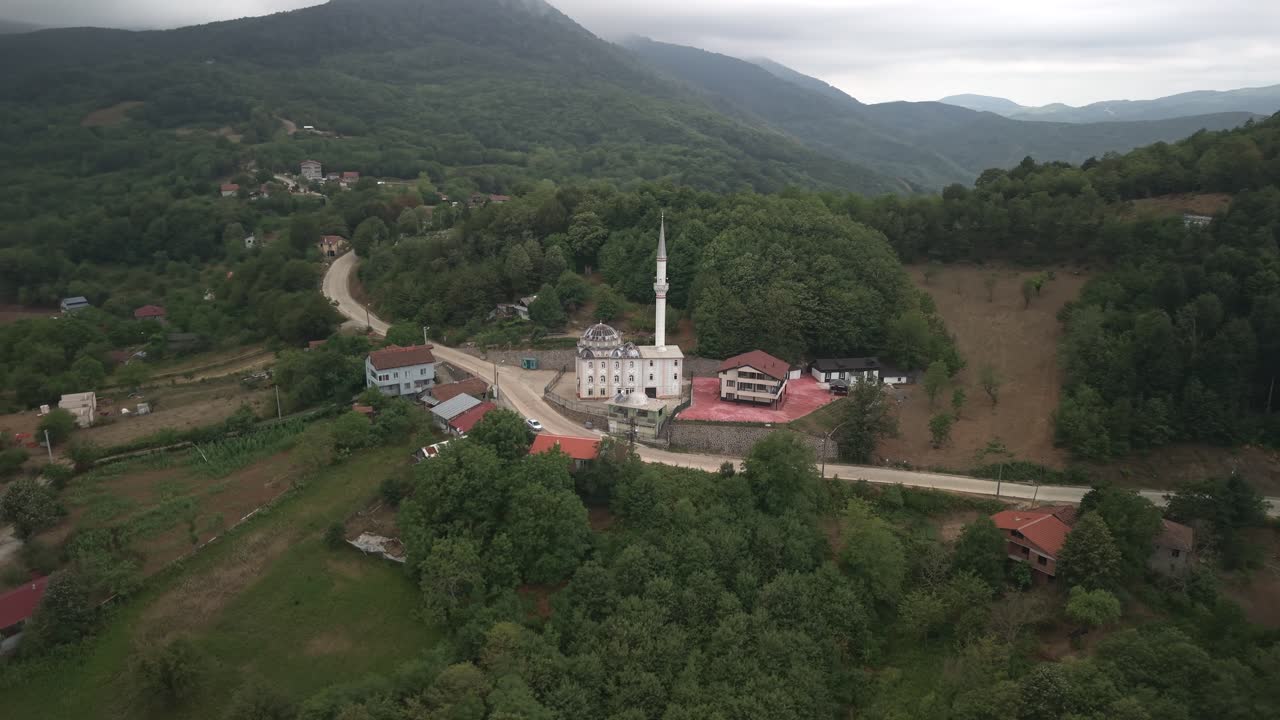 Bulutlu bir günde ye��il tepelerle çevrili Mecidiye köyündeki geleneksel bir Türk camisinin havadan dairesel çekimi.