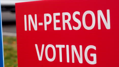 Red-In-Person-Voting-Sign-Blowing-in-the-Wind-Outside-Close-Up