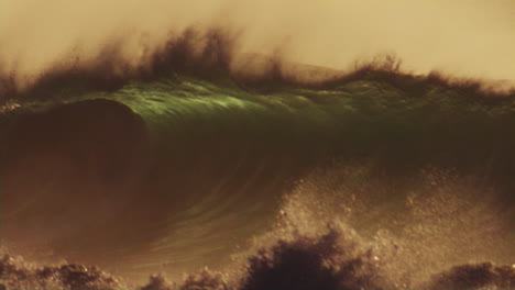 slow motion waves rolling at golden hour in the pacific ocean, glowing mist and sunlight reflecting off the water