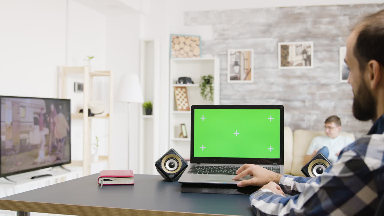 Man using laptop with green screen at home