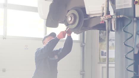 mecánico de automóviles que trabaja en el sistema de frenos de un automóvil