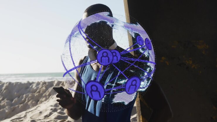 Mand, der står på stranden ved siden af en betonpille og bruger en smartphone, der viser teknologi med AR-netværksklode.