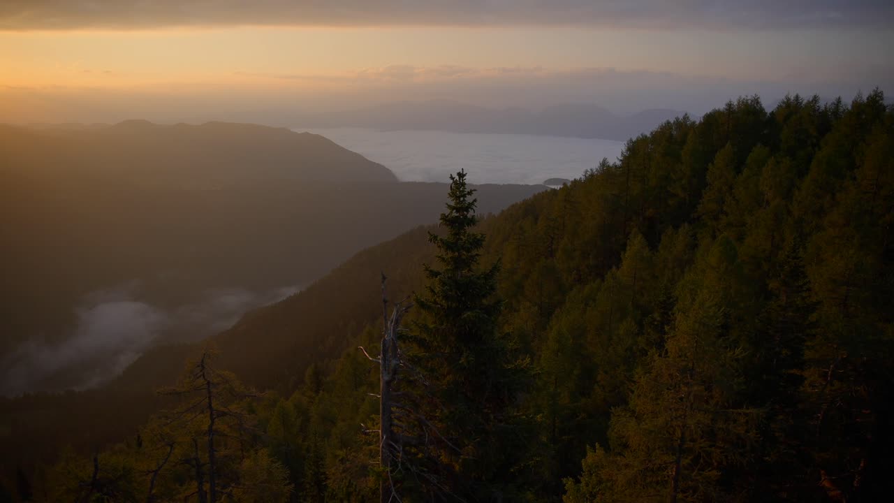 movimiento de abajo hacia arriba con un cardán de metraje en las montañas eslovenas en los alpes al amanecer en hermosos colores con una cámara que avanza lentamente con vistas a un valle bajo la niebla