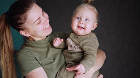 cheerful caucasian mom holding her beautiful baby. loving mother leans to her child. blurred backdrop.