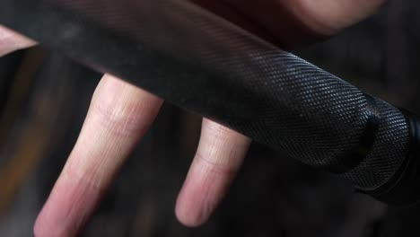 slow motion close up of bodybuilder gripping weightlifting bar, dark background