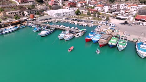 aerial orbit around boat entering port with large vessels docked