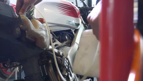 close-up footage of technician working on transferring brake fluid for motorcycle