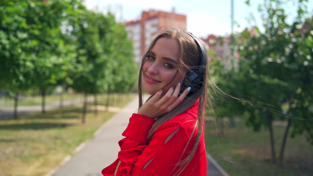 Smiling teenage girl with headphones outdoors. Portrait of young attractive girl in urban background listening to the music with headphones
