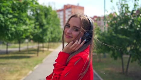 smiling teenage girl with headphones outdoors. portrait of young attractive girl in urban background listening to the music with headphones