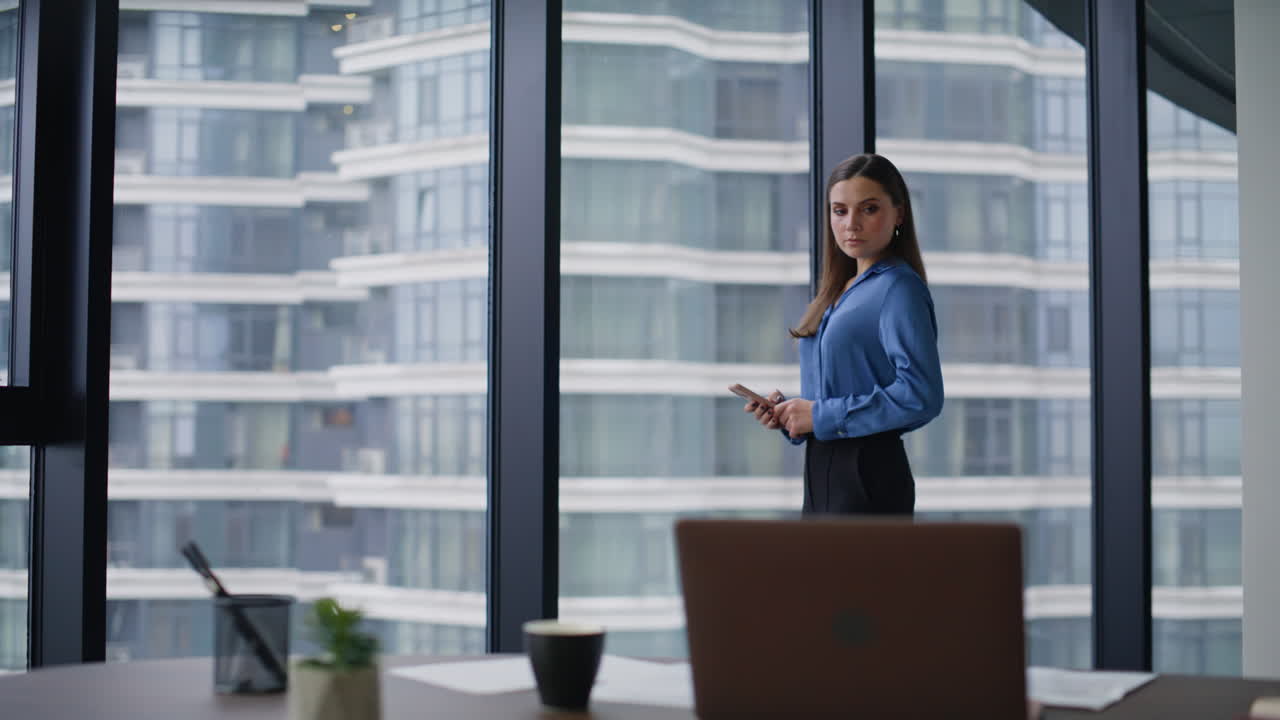 Serious businesswoman looking smartphone receiving message in corporate office
