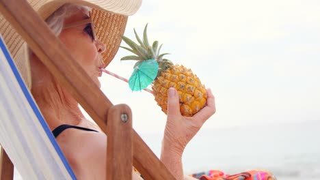 mujer jubilada bebiendo cócteles y acostada en la silla de sol