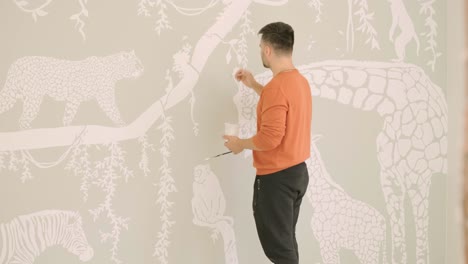 the artist is decorating walls by drawings in the children's room. art painting of the walls in the new house. repair works.