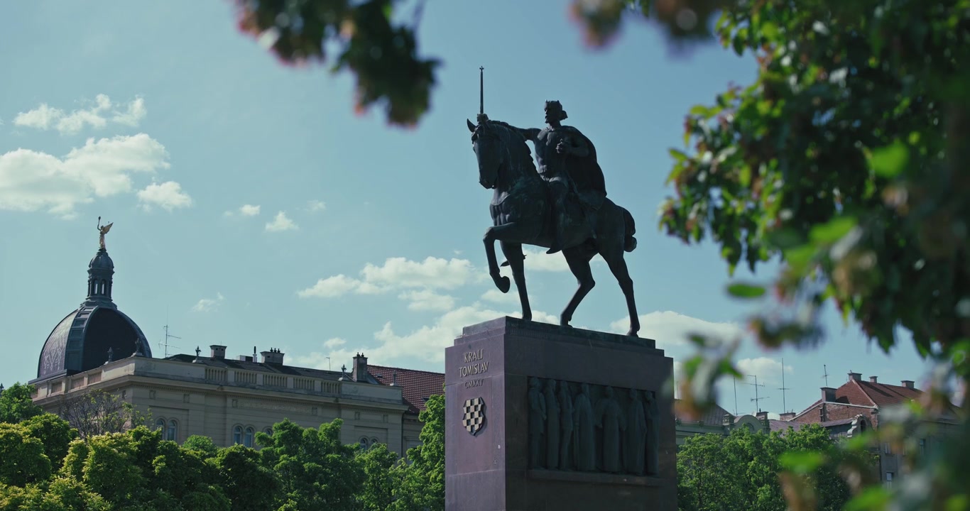 Silhouette della statua del Re Tomislav a Zagabria, Croazia, sullo sfondo di alberi ed edifici storici.