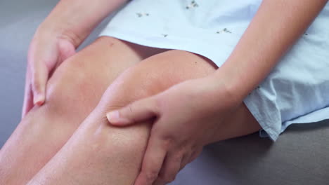 close-up of an individual squeezing, pressing, and pinching her knees to relieve the swelling and inflammation