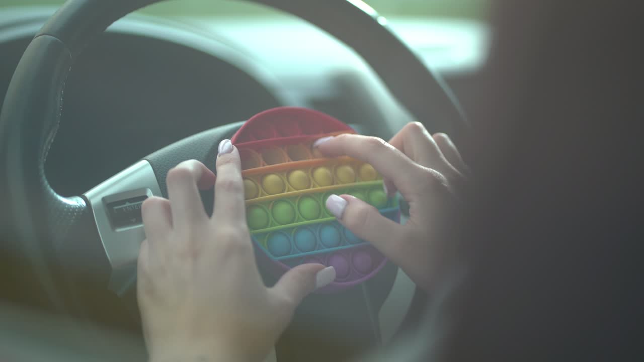 Woman using pop it or simple dimple in car.