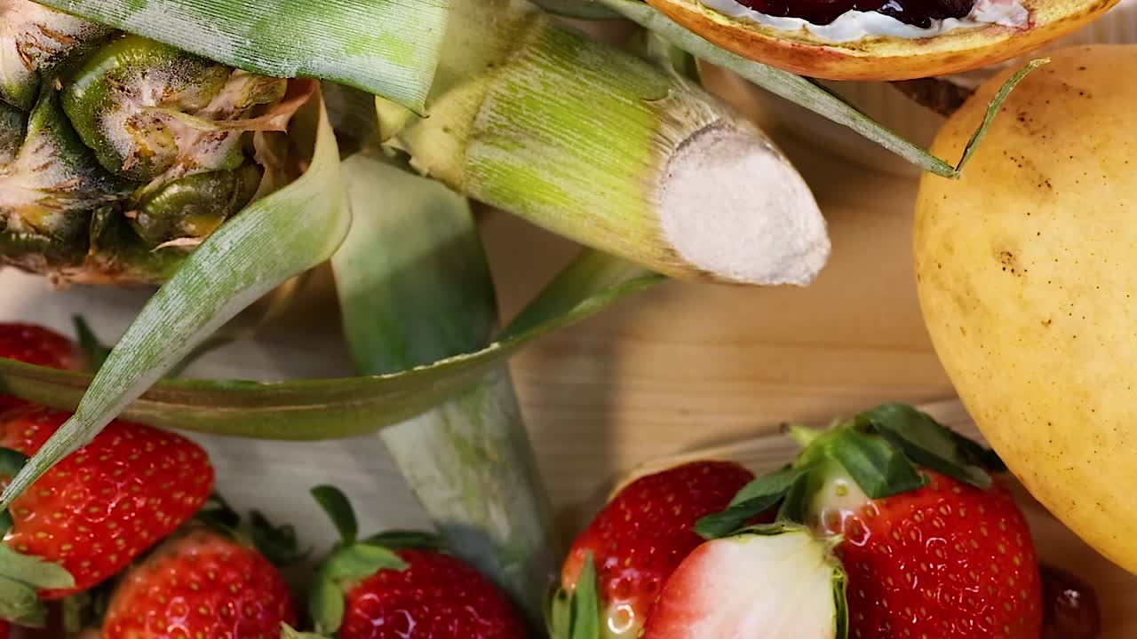 A colorful assortment of sliced mangoes, kiwis, strawberries, and whole bananas on a wooden surface.