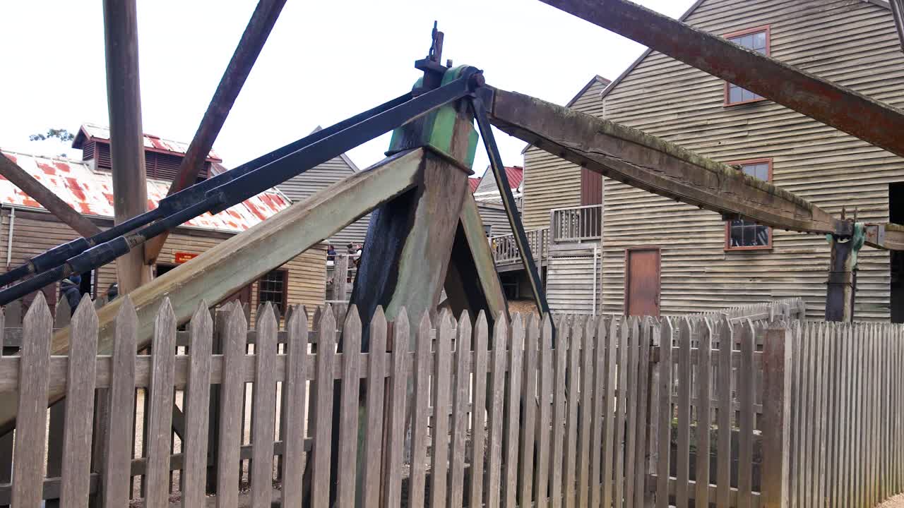 Wooden mining equipment behind a fence at Sovereign Hill, Ballarat. Overcast lighting highlights the rustic, historical setting