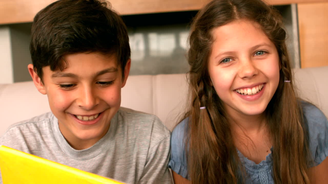 hermanos sonriendo a la cámara en el sofá