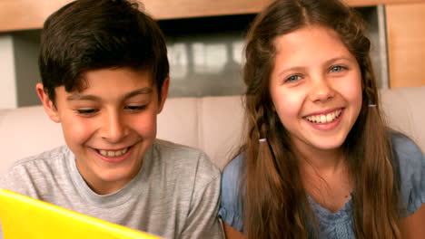 Siblings-smiling-at-camera-on-couch