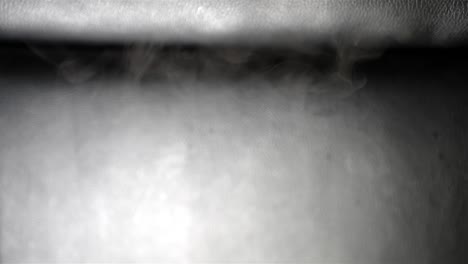 close up of wispy cool smoke on black leather dropping from top to bottom